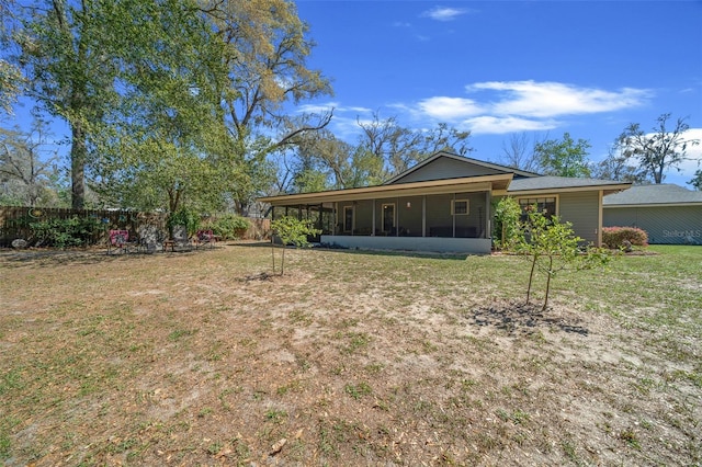 exterior space with fence, a lawn, and a sunroom