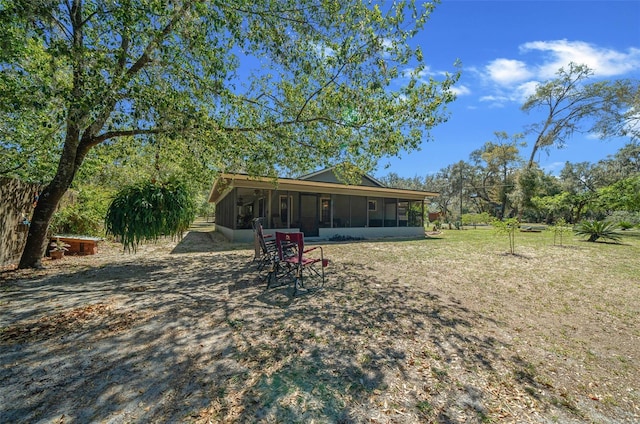 rear view of house featuring a lawn and a sunroom