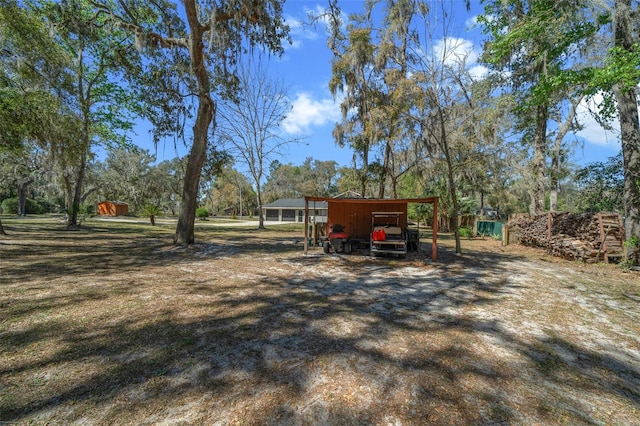 view of yard featuring an outbuilding, a carport, and driveway