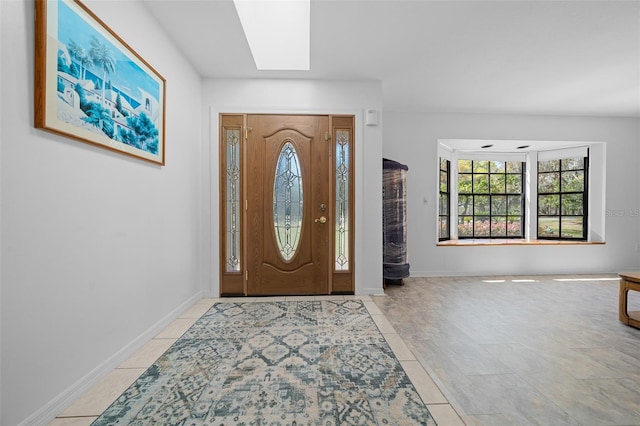 entryway with light tile patterned floors, a skylight, and baseboards