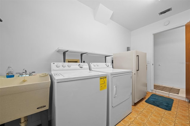 washroom with visible vents, washing machine and dryer, laundry area, and a sink