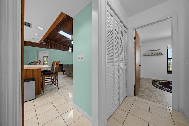 corridor featuring visible vents, vaulted ceiling with skylight, and light tile patterned flooring