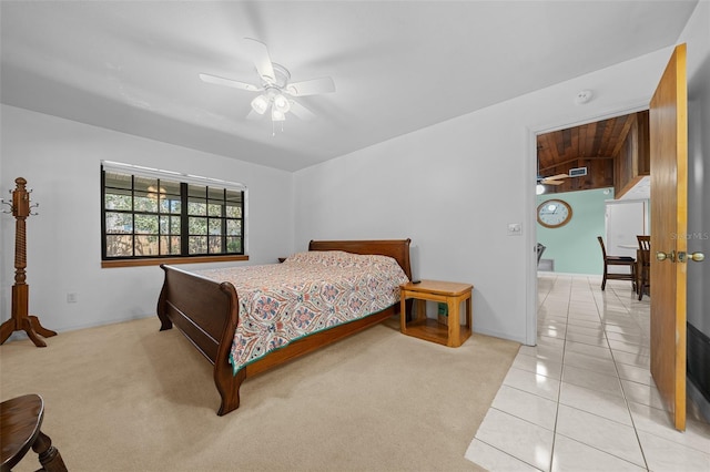 bedroom with light carpet, light tile patterned floors, and a ceiling fan