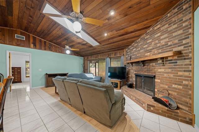 living room featuring lofted ceiling with skylight, light tile patterned flooring, a fireplace, and visible vents