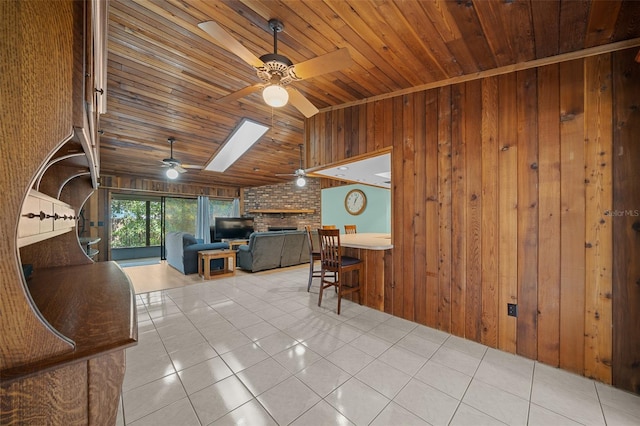 living room with wooden walls, a fireplace, lofted ceiling with skylight, tile patterned floors, and wooden ceiling