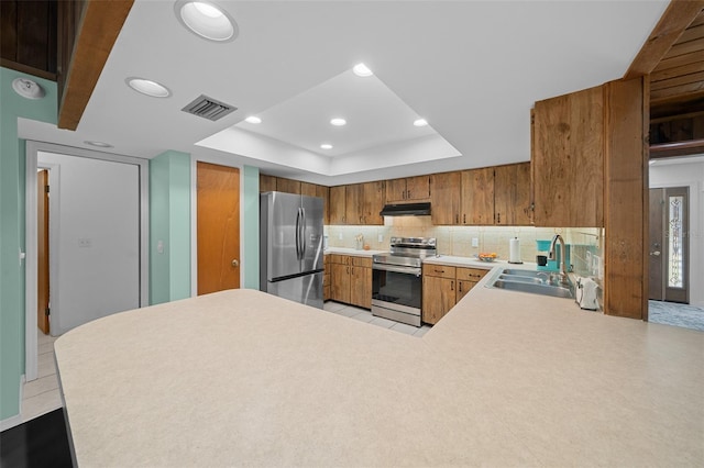 kitchen with visible vents, a sink, under cabinet range hood, appliances with stainless steel finishes, and a raised ceiling