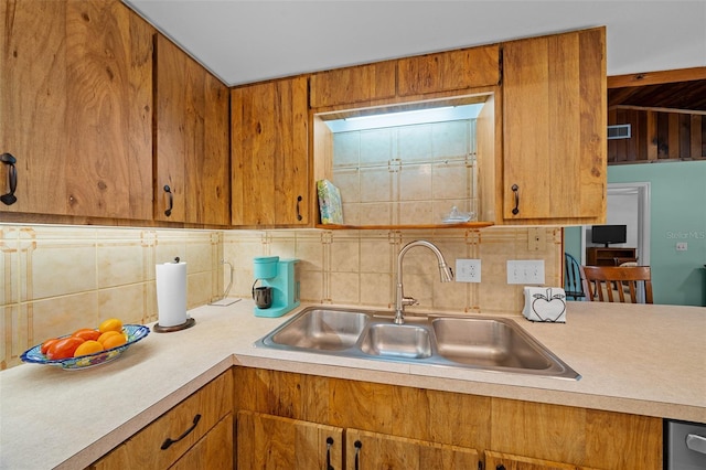 kitchen with decorative backsplash, light countertops, brown cabinetry, and a sink