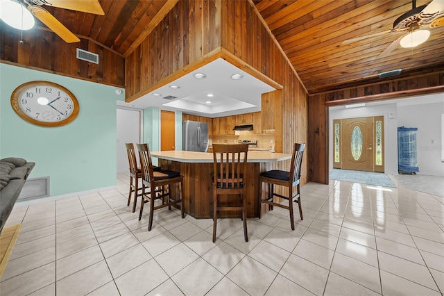 dining space featuring wooden walls, visible vents, light tile patterned flooring, ceiling fan, and wooden ceiling