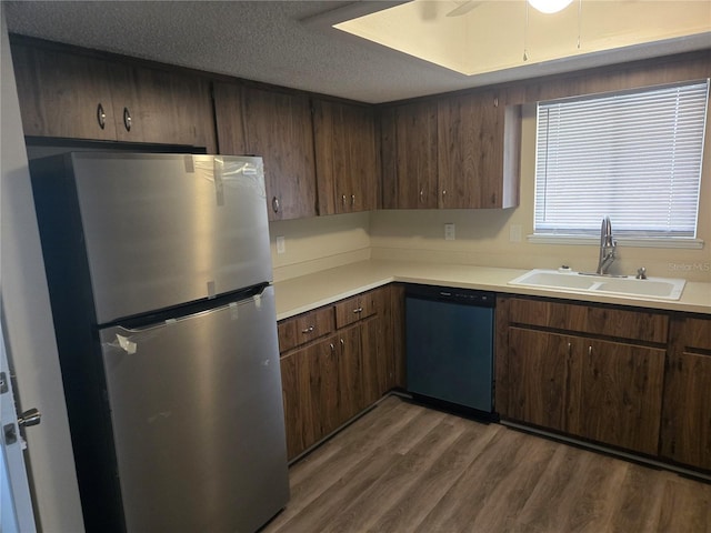 kitchen with dishwasher, wood finished floors, freestanding refrigerator, light countertops, and a sink