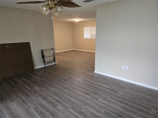 unfurnished room featuring a ceiling fan, visible vents, baseboards, and dark wood-type flooring