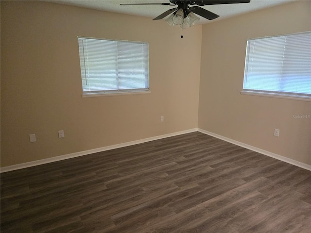 spare room with dark wood-style flooring, a ceiling fan, and baseboards