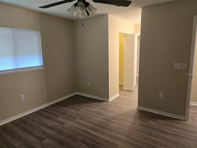 spare room featuring a textured ceiling, dark wood finished floors, a ceiling fan, and baseboards