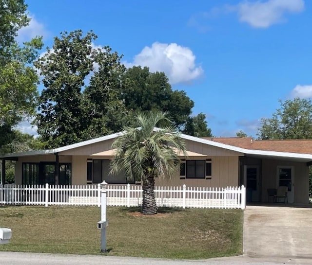 view of front of property with concrete driveway, a carport, and a fenced front yard