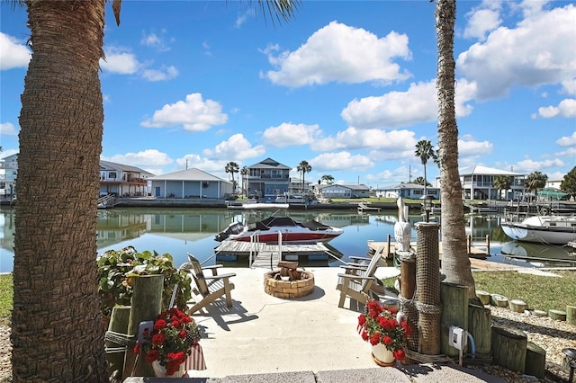 view of dock with a residential view, a water view, boat lift, and an outdoor fire pit