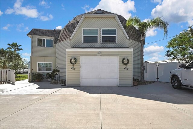 view of front of home featuring a garage, a shingled roof, driveway, and a gate