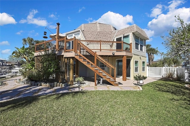 back of property featuring a lawn, fence, stairway, roof with shingles, and a wooden deck