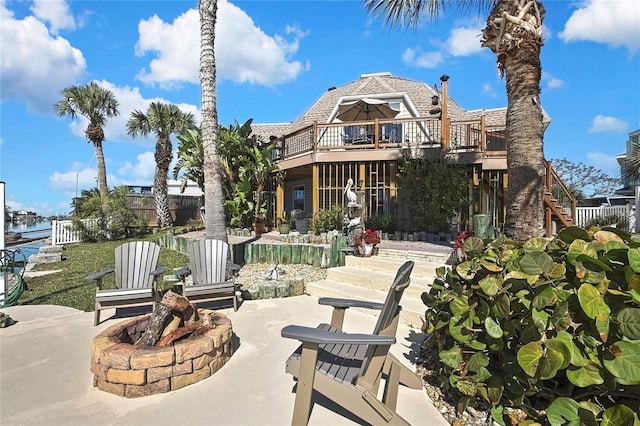 rear view of house with a water view, fence, an outdoor fire pit, stairs, and a patio area