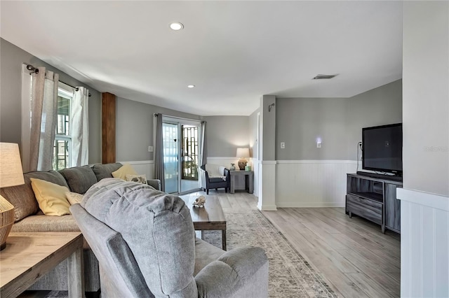 living room with recessed lighting, visible vents, light wood-style flooring, and a wainscoted wall