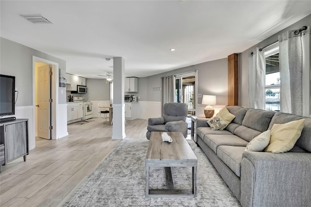 living room featuring visible vents, light wood-style flooring, and a ceiling fan