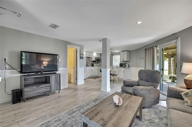 living room featuring a wainscoted wall, recessed lighting, light wood-style floors, and visible vents