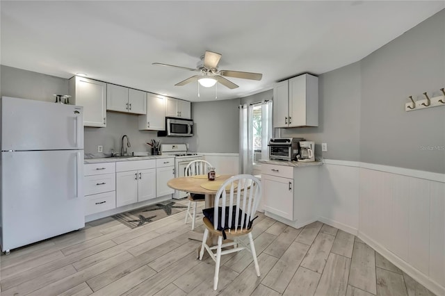 kitchen featuring a sink, light wood-type flooring, white appliances, and light countertops