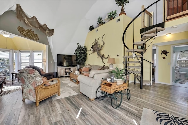 living area featuring baseboards, stairs, a towering ceiling, and wood finished floors