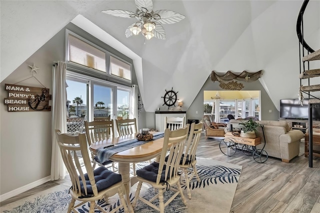 dining room featuring a towering ceiling, a ceiling fan, baseboards, and light wood finished floors