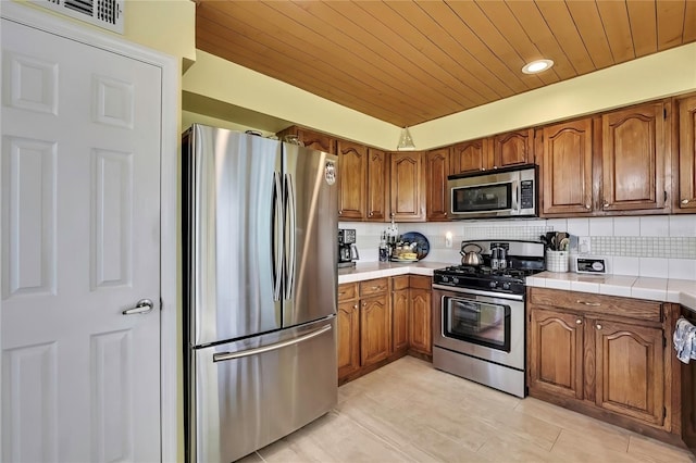 kitchen featuring stainless steel appliances, brown cabinets, backsplash, and wooden ceiling