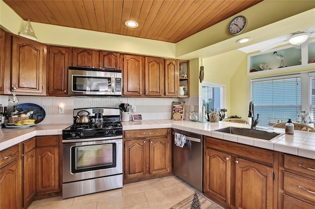 kitchen with tasteful backsplash, brown cabinets, appliances with stainless steel finishes, and a sink