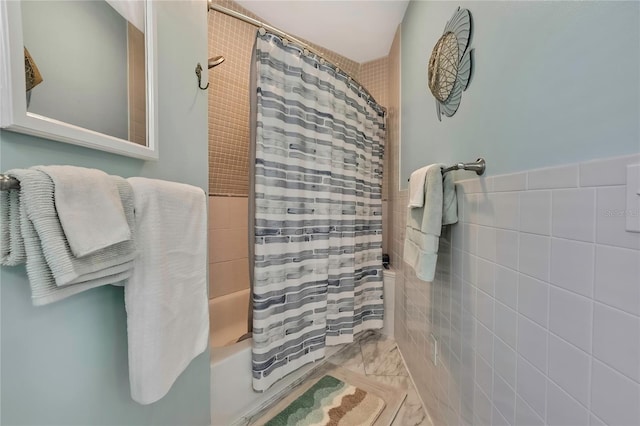 bathroom with a wainscoted wall, shower / bath combination with curtain, and tile walls