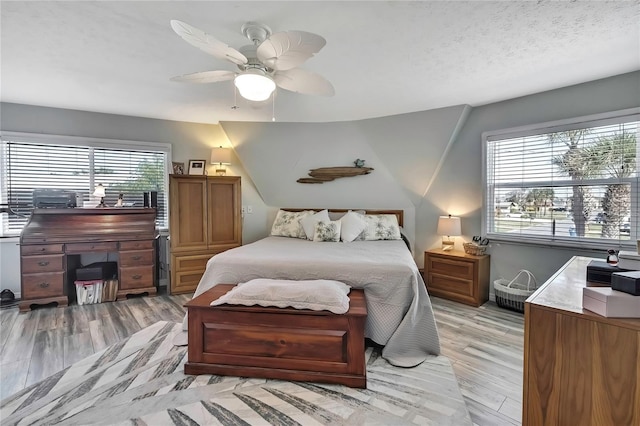 bedroom with multiple windows, a textured ceiling, light wood-type flooring, and a ceiling fan