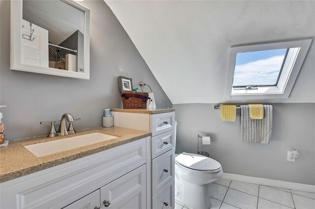 bathroom with lofted ceiling with skylight, toilet, tile patterned flooring, a shower, and vanity