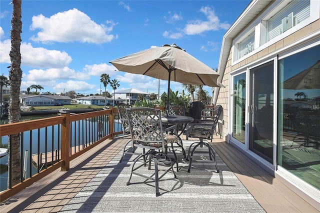 wooden terrace featuring outdoor dining area and a water view