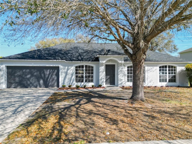 single story home featuring a garage, concrete driveway, and stucco siding