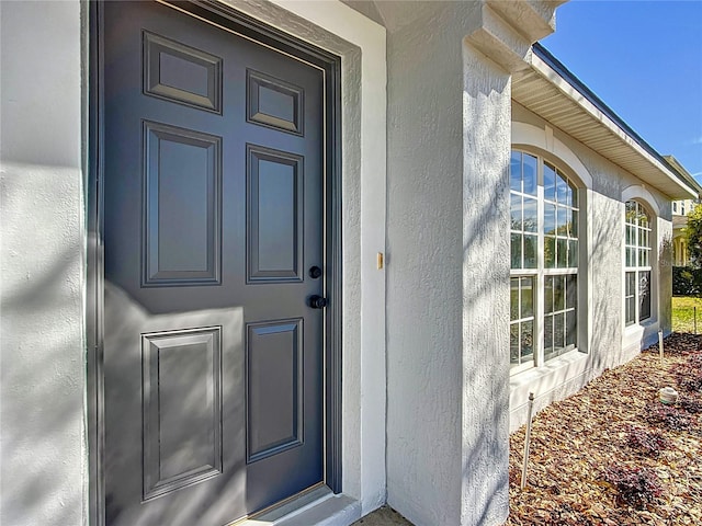 doorway to property featuring stucco siding