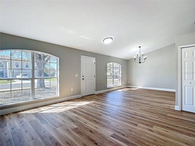 foyer featuring baseboards, a chandelier, vaulted ceiling, and wood finished floors