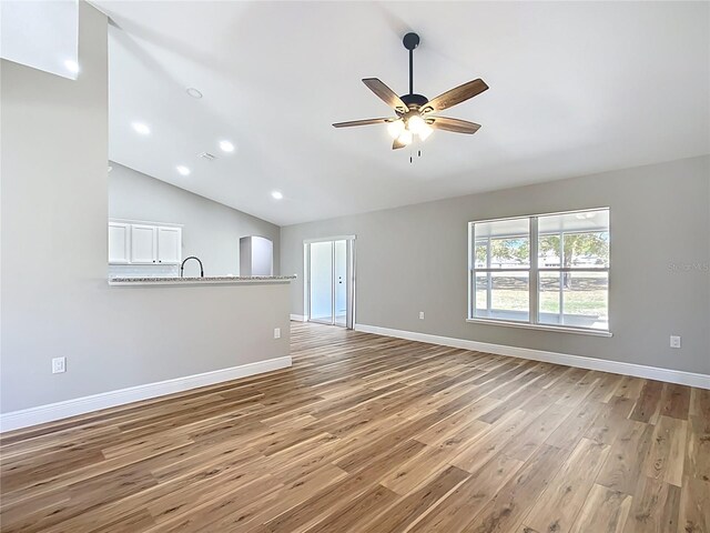 unfurnished living room featuring a ceiling fan, baseboards, vaulted ceiling, and light wood finished floors