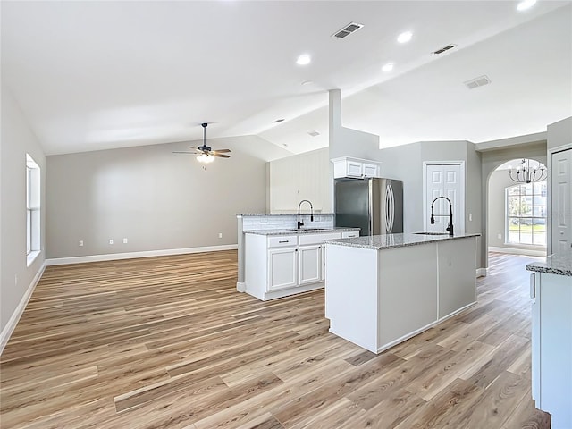 kitchen with lofted ceiling, visible vents, white cabinets, and freestanding refrigerator