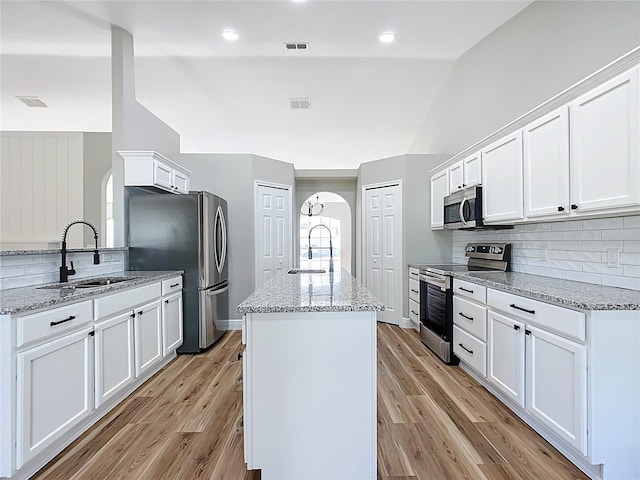 kitchen with a kitchen island, visible vents, stainless steel appliances, and a sink