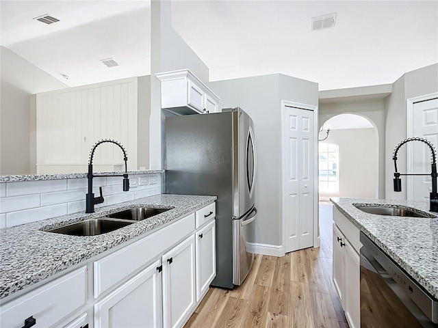 kitchen featuring appliances with stainless steel finishes, a sink, visible vents, and white cabinets