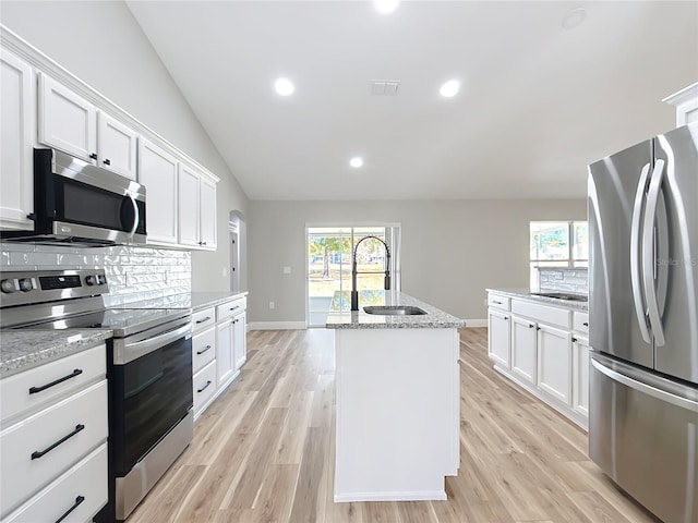 kitchen featuring stainless steel appliances, backsplash, light wood-style floors, white cabinetry, and a sink