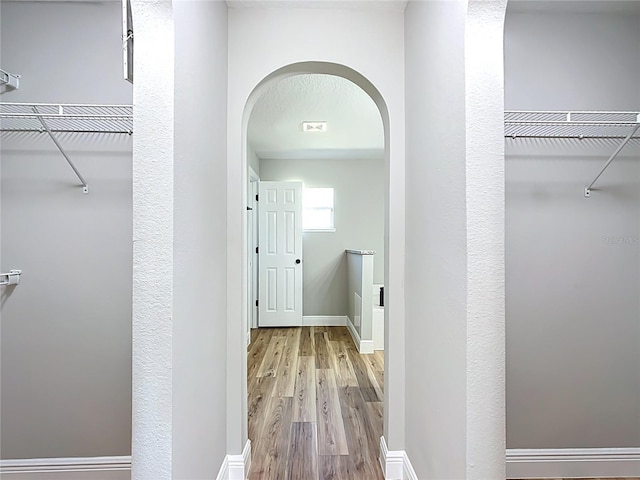 spacious closet with arched walkways and wood finished floors