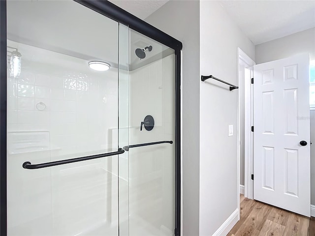 bathroom with a stall shower, wood finished floors, and baseboards