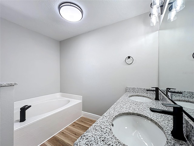 bathroom featuring double vanity, wood finished floors, a sink, and a bath