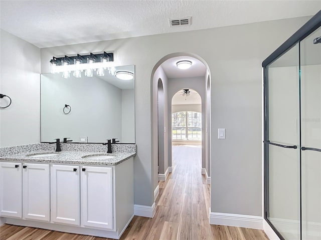 full bath with visible vents, a sink, a textured ceiling, and wood finished floors