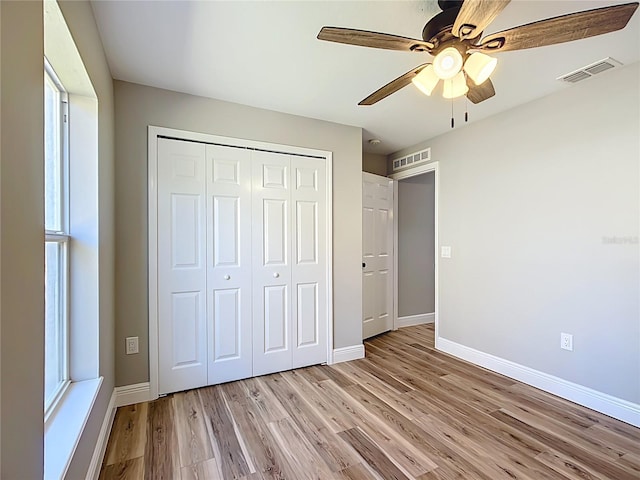 unfurnished bedroom featuring light wood finished floors, a closet, visible vents, and baseboards