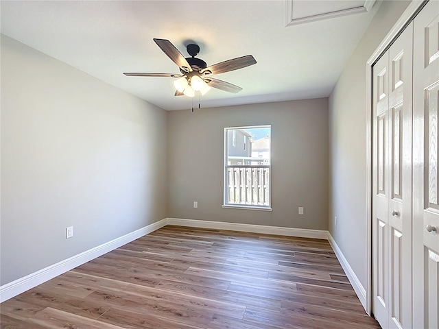 unfurnished bedroom featuring ceiling fan, baseboards, a closet, and wood finished floors