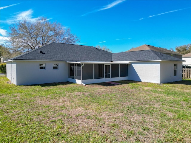 back of property with a sunroom, a shingled roof, stucco siding, and a yard