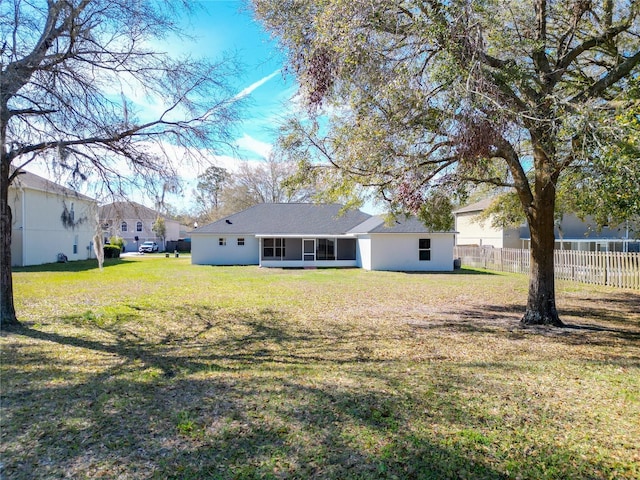 back of property with stucco siding, a lawn, and fence