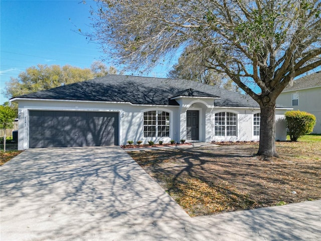 single story home featuring driveway, an attached garage, and stucco siding